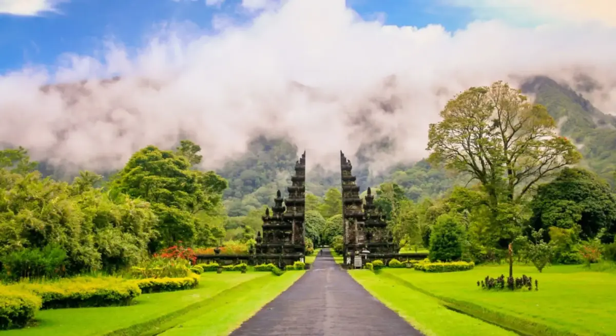Traditional Balinese split gate surrounded by tropical gardens and mountains, evoking a serene arrival by private jet charter