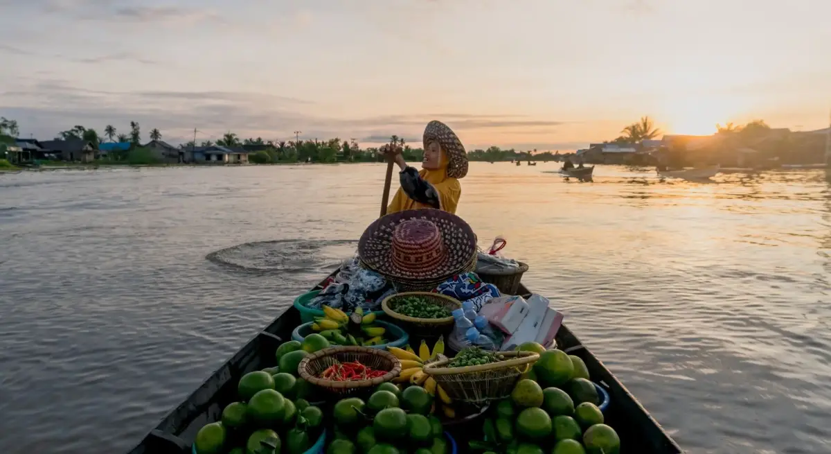 Local vendor paddling a wooden boat at sunrise on a calm river near Batulicin, South Kalimantan