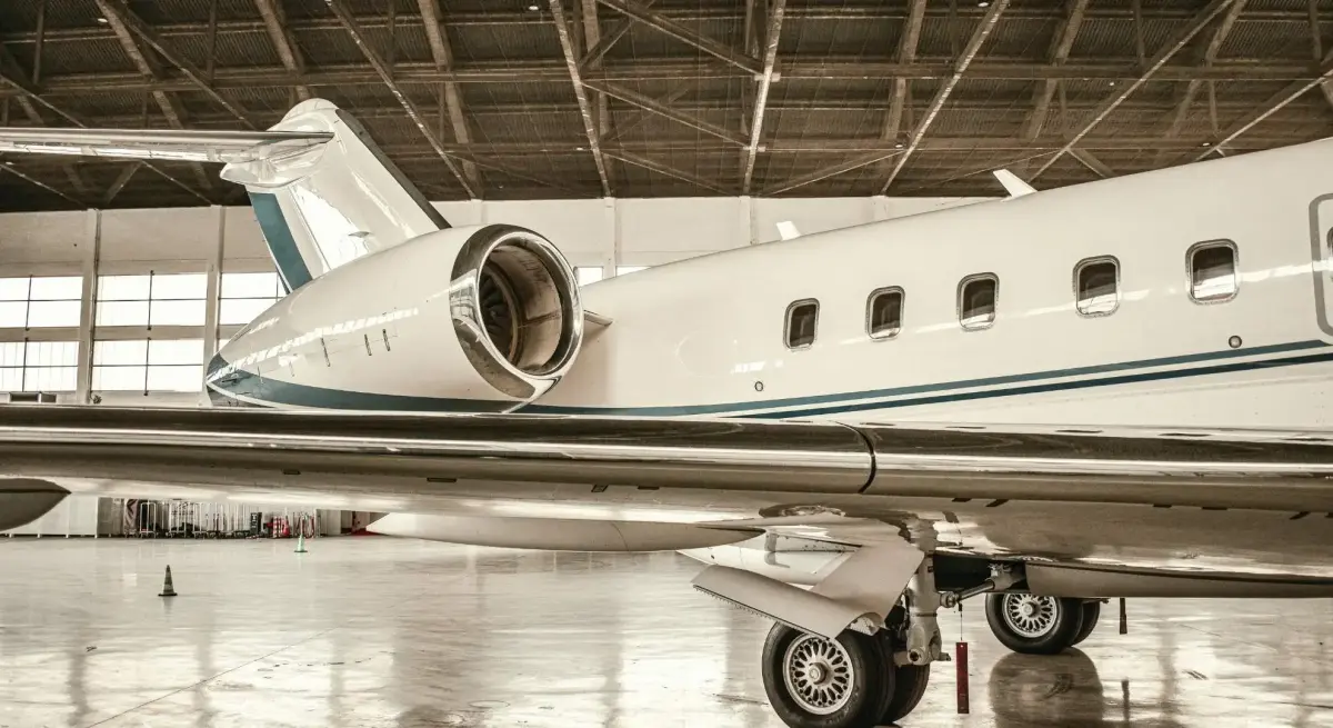 White business jet with teal livery parked in a private aviation hangar, showcasing Hong Kong corporate charter travel