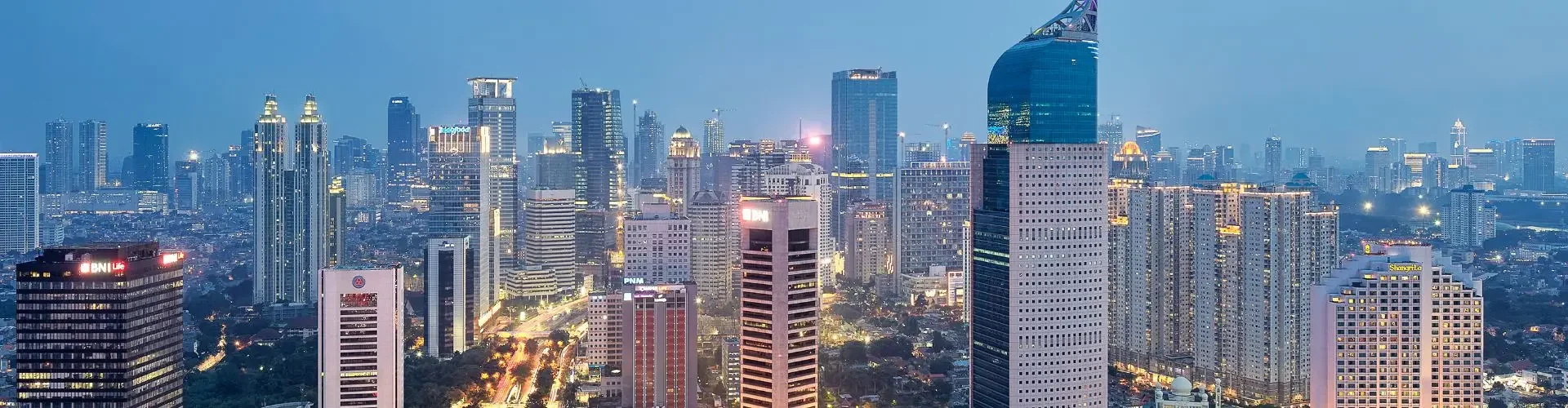 Private Jet Charter to Jakarta Halim Airport (HLP/WIHH) Jakarta city skyline at dusk with illuminated skyscrapers and BNI tower, aerial view representing private jet charter destination in Indonesia