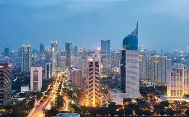 Private Jet Charter to Jakarta Halim Airport (HLP/WIHH) Jakarta city skyline at dusk with illuminated skyscrapers and BNI tower, aerial view representing private jet charter destination in Indonesia