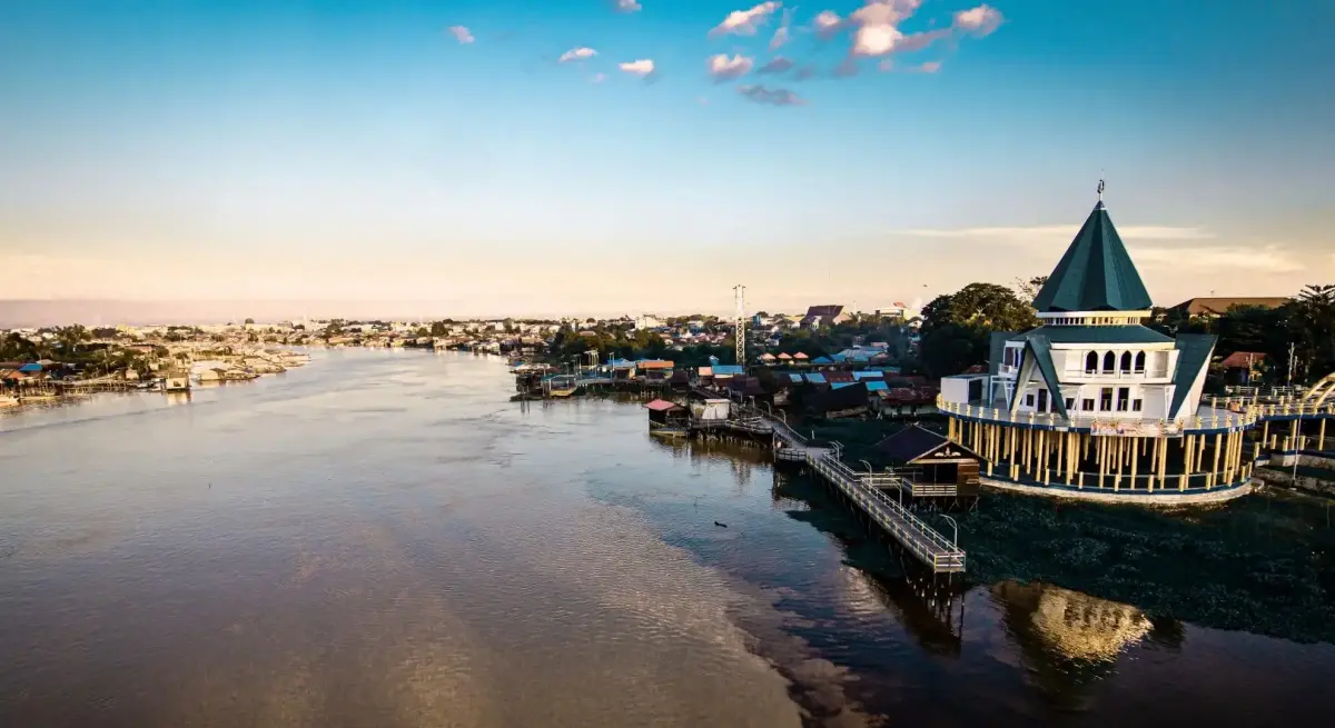 Aerial view of Palangka Raya riverfront at sunset, featuring a waterfront pavilion on the Kahayan River with the city skyline