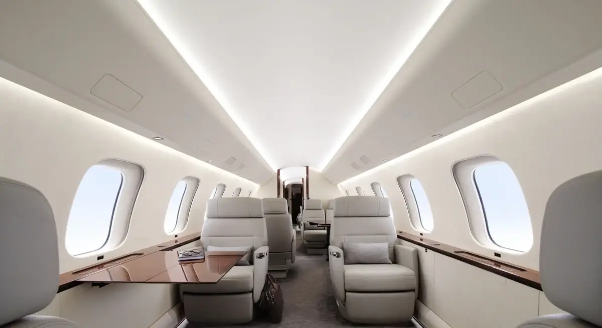 Spacious private jet cabin with cream leather recliner seats, warm ambient lighting, and large oval windows