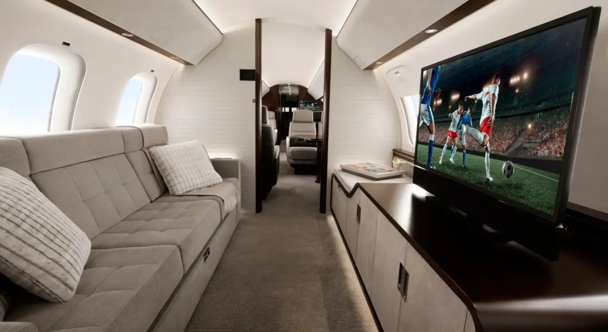 A private jet cabin interior featuring a sofa, entertainment display, and seats for the Jakarta to Palangka Raya route