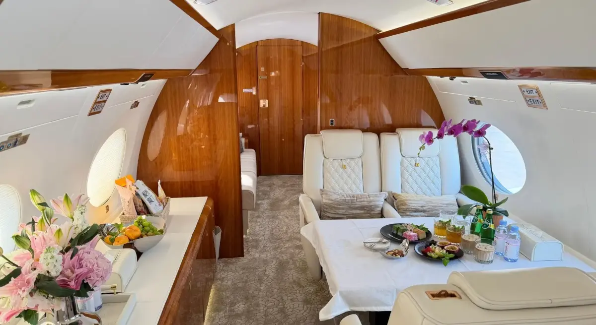 Private jet cabin interior with leather seatin and a dining table with fresh fruit on a Jakarta to Singapore charter flight