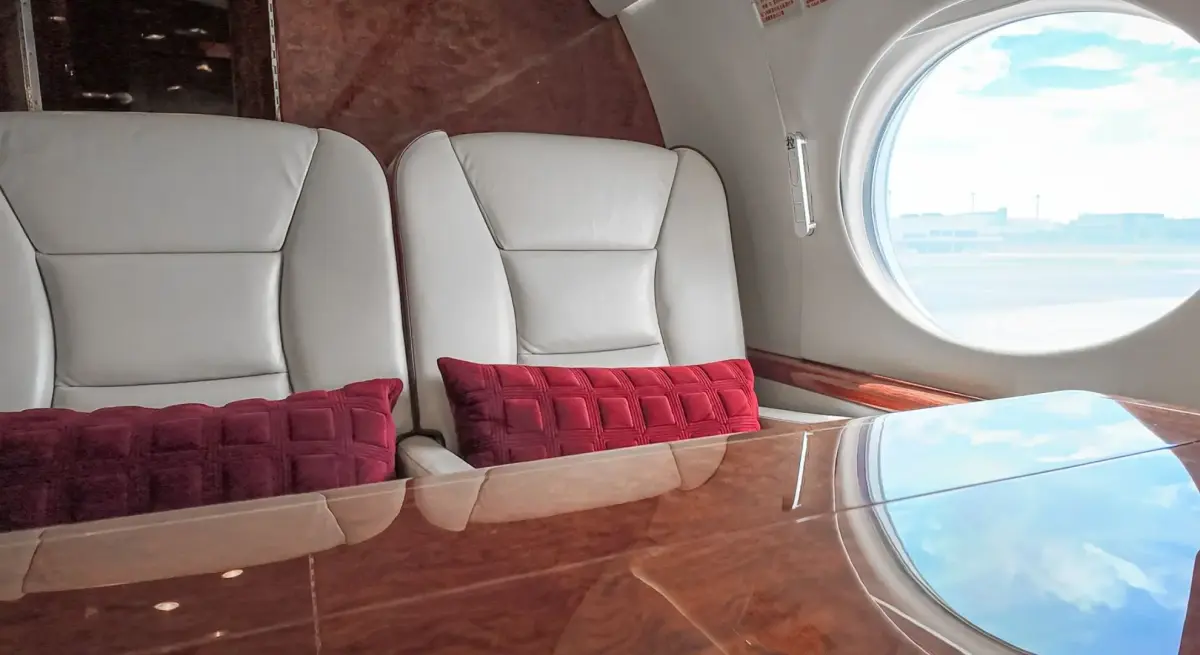 White leather private jet cabin seats with red cushions with a Gulfstream window on a Jakarta to Surabaya charter flight