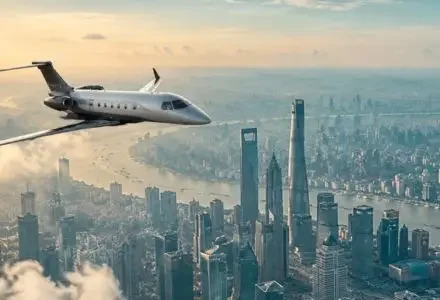 Private jet flying over a major Asian city skyline at sunset, ideal for luxury charter flights from Hong Kong