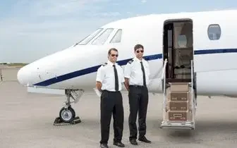 Two Jetbay pilots in uniform standing beside a private jet on the tarmac, ready to welcome charter passengers aboard