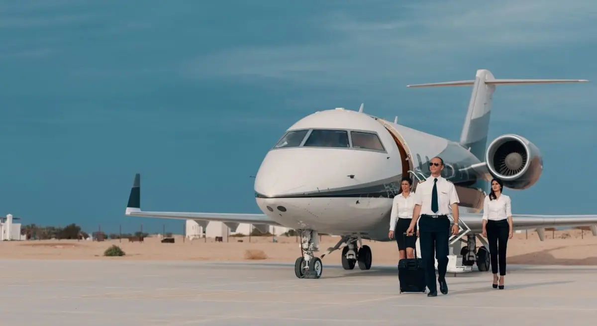 Private jet pilot and cabin crew walking across tarmac, representing professional crew available for charter in Indonesia