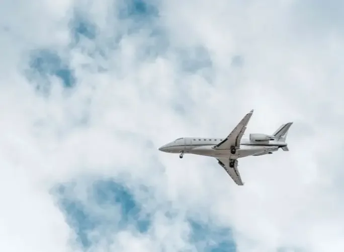 Private jet flying overhead, illustrating freedom and flexibility of private jet travel compared to business class