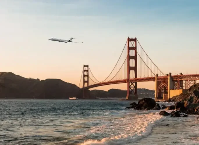 Private jet flying over the Golden Gate Bridge at sunset, symbolising charter flights to the US