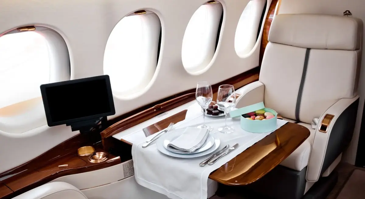 Private jet cabin dining setup with fine china, wine glasses, macarons, and a table, ideal for Hong Kong charter flights