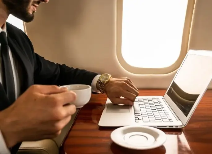 Business executive working on laptop aboard a private jet charter, ideal for mining professionals travelling across Indonesia