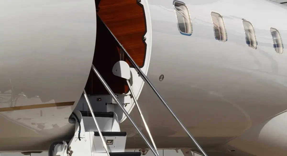 Private jet stairway with rich wood-panelled interior, highlighting boarding experience compared to business class travel