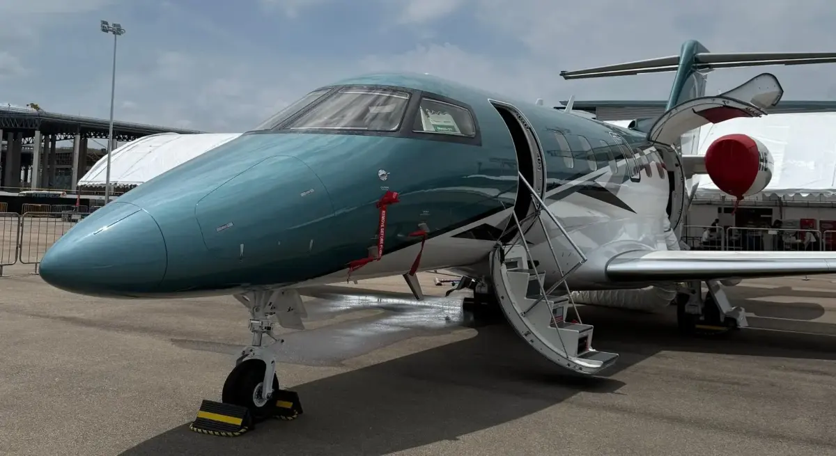 Sleek green and silver business jet with open cabin door displayed at Singapore Airshow aviation exhibition