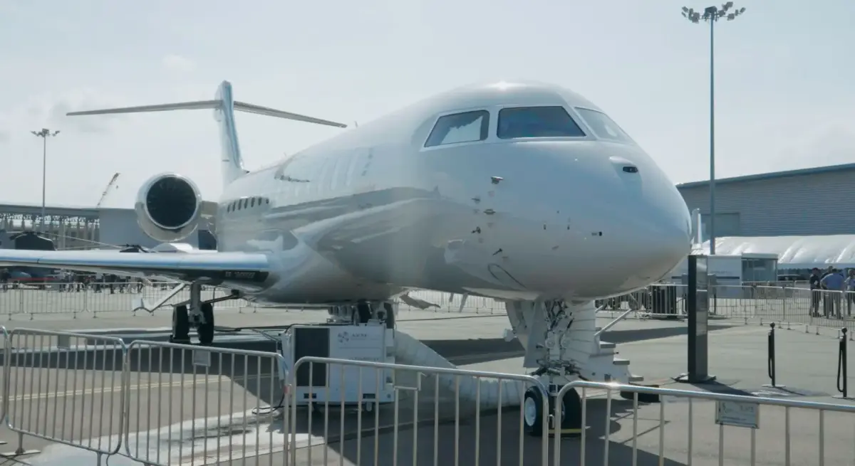 White business jet on display at Singapore Airshow with viewing barriers and aviation infrastructure