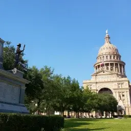 Texas State Capitol building with distinctive dome and columns under clear blue sky in Austin