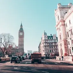 Big Ben clock tower and historic London architecture viewed from busy street with classic cars
