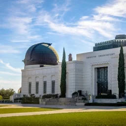 Griffith Observatory with distinctive copper dome and white Art Deco architecture under blue sky