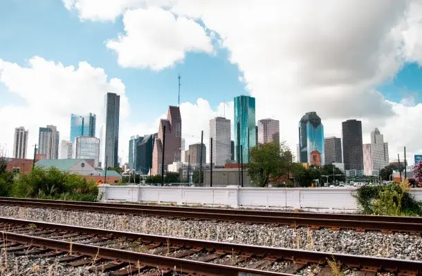 Houston downtown skyline with modern skyscrapers and railway tracks in foreground under cloudy sky