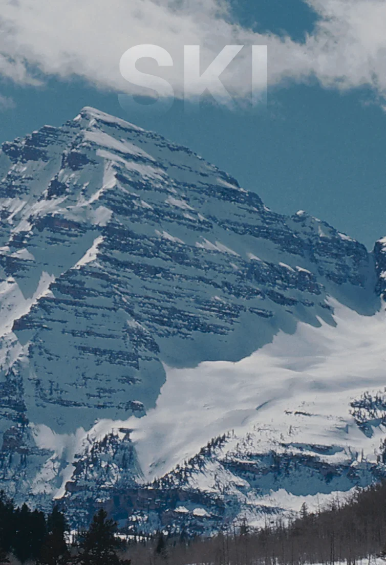 Snow-covered mountain peaks and evergreen forests create a dramatic alpine landscape in Aspen