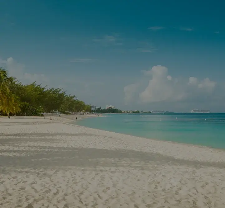 Pristine white sand beach with swaying palm trees and turquoise waters in Grand Cayman, Caribbean