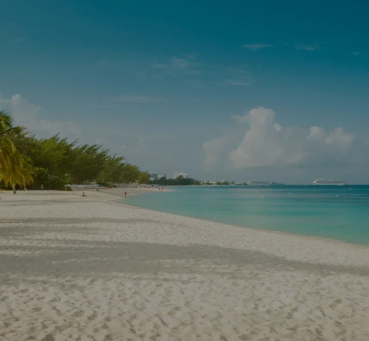 Pristine white sand beach with swaying palm trees and turquoise waters in Grand Cayman, Caribbean