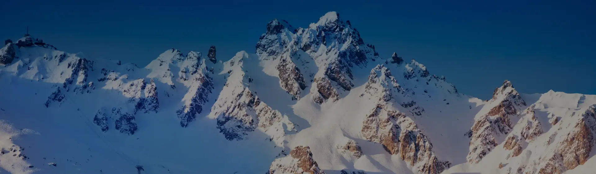 Snow-covered mountain peaks of Sun Valley ski resort under clear blue skies, premier destination for luxury skiing