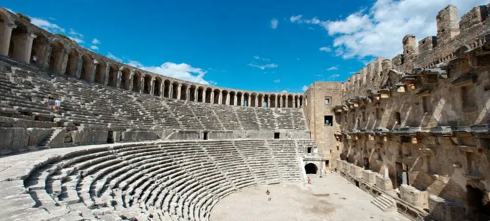 Ancient Roman amphitheater in Antalya showcasing well-preserved stone seating and arches under bright blue sky