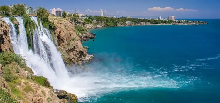 Dramatic Duden Waterfalls cascading into turquoise Mediterranean waters near Antalya's luxury resort coastline