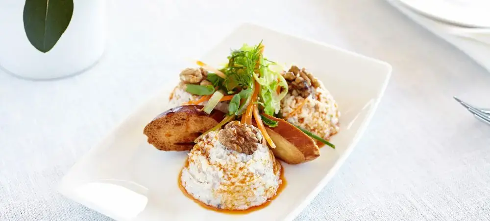 Gourmet Turkish cuisine featuring walnut-crusted cheese medallions with roasted potatoes and fresh herbs