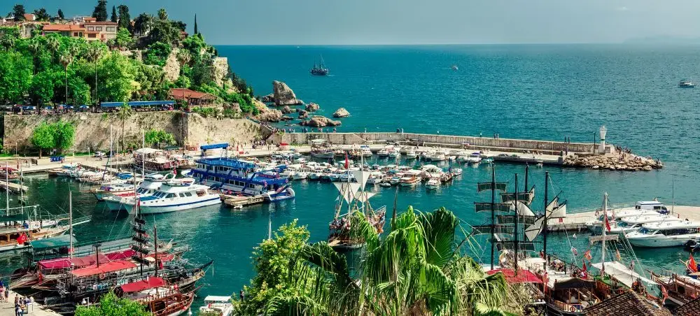 Scenic Antalya harbor with luxury yachts, traditional boats, and Mediterranean coastline views