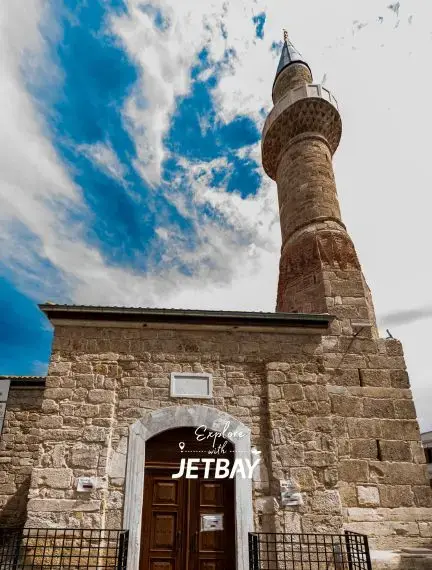 Historic stone mosque with traditional minaret in Antalya's old town under dramatic blue sky