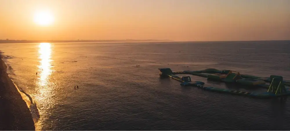 Golden sunset over Antalya's Mediterranean coastline with inflatable water park attractions for luxury travelers
