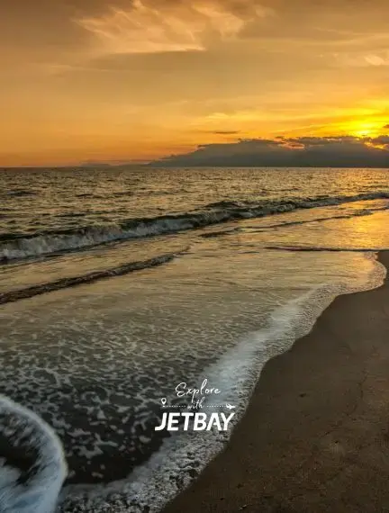 Golden sunset over Mediterranean waves washing onto pristine Antalya beach with distant mountains