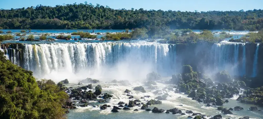 Spectacular Iguazu Falls cascading over rocky cliffs surrounded by lush rainforest in Argentina