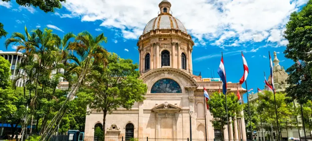 Historic colonial cathedral with ornate dome surrounded by palm trees in downtown Asuncion Paraguay