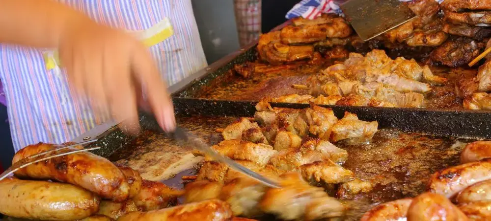 Traditional Paraguayan grilled meats and sausages sizzling on outdoor barbecue grill in Asuncion market