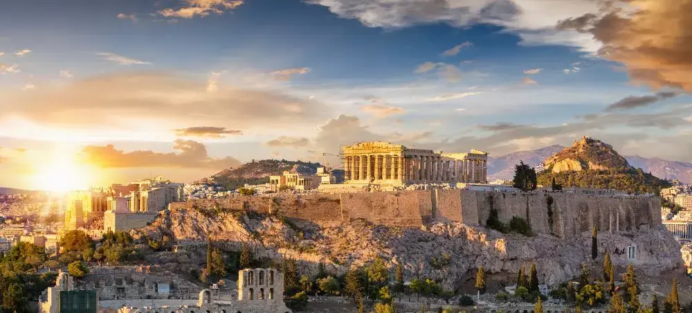 Golden sunset illuminating the ancient Acropolis and Parthenon temple overlooking Athens cityscape