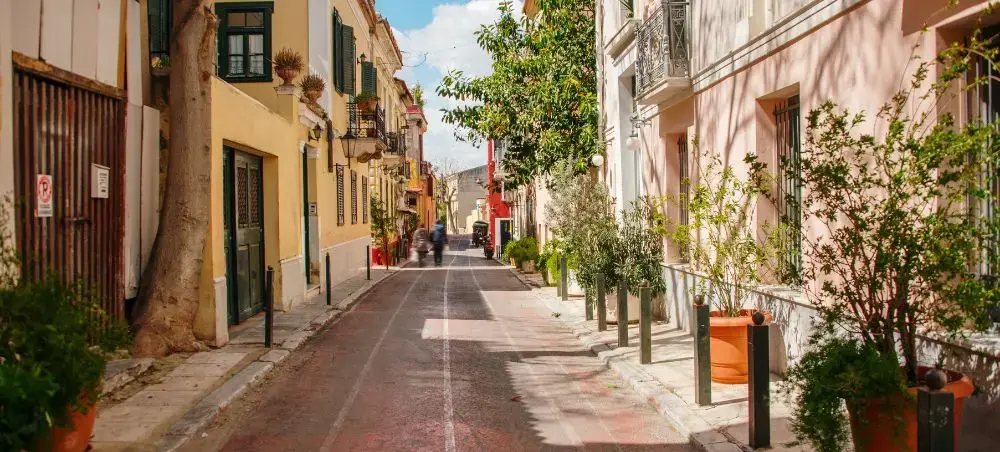Charming cobblestone street in Athens lined with colorful Mediterranean buildings and lush greenery