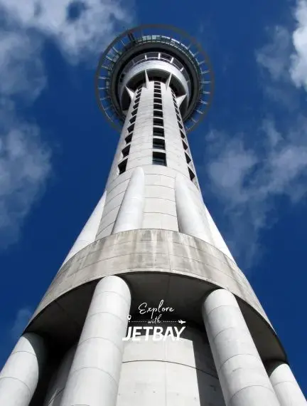 Auckland Sky Tower observation deck rising against blue sky with Jetbay branding for New Zealand travel