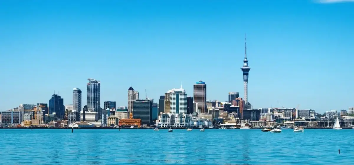 Auckland skyline featuring Sky Tower and modern skyscrapers reflected in pristine harbor waters