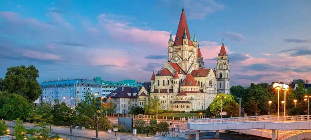 Historic Austrian cathedral with red spires illuminated at sunset, showcasing Austria's architectural heritage