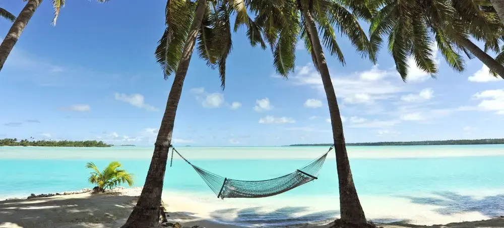 Hammock suspended between palm trees on pristine Bahamas beach with turquoise waters and white sand
