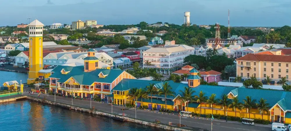 Colorful waterfront buildings and yellow lighthouse in Nassau harbor showcase Bahamas luxury travel destination