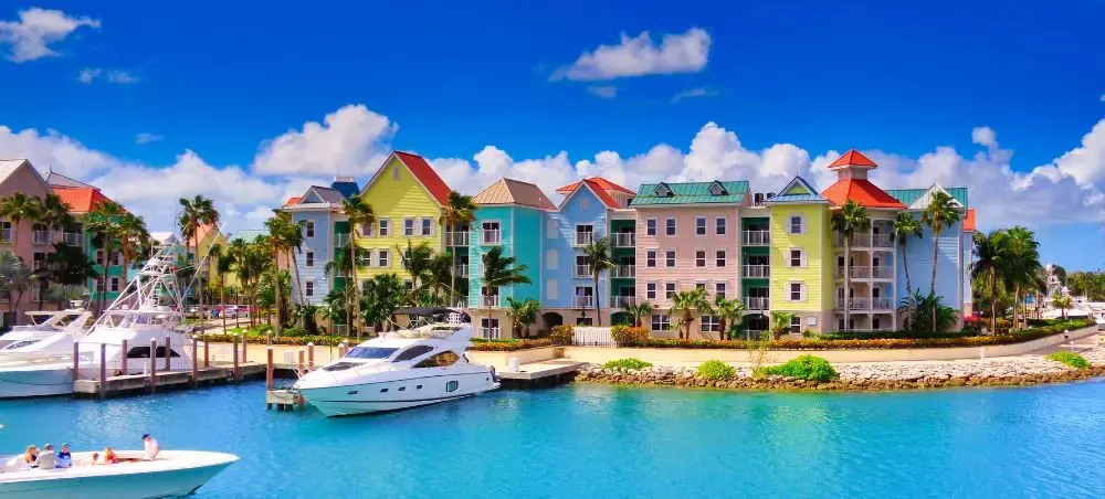 Vibrant waterfront resort buildings in tropical pastels overlooking turquoise harbor with luxury yachts in Nassau