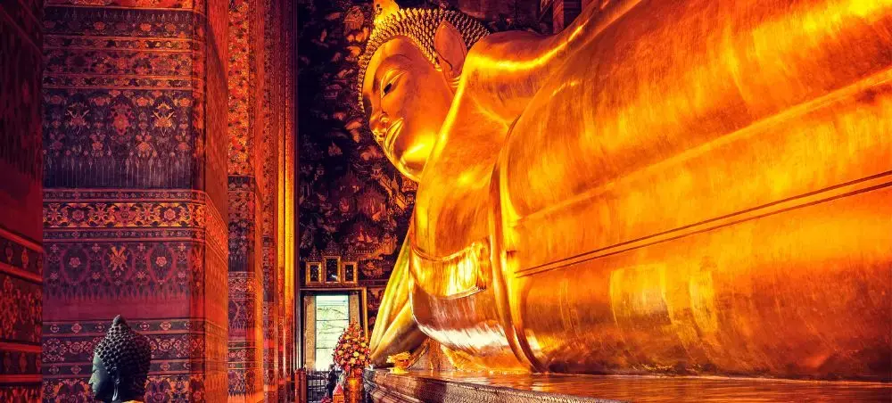 Massive golden reclining Buddha statue inside ornate Thai temple showcasing Bangkok's spiritual heritage
