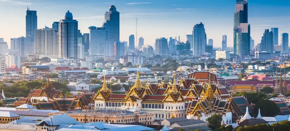 Bangkok skyline showcasing golden temple rooftops of Grand Palace against modern skyscrapers in Thailand