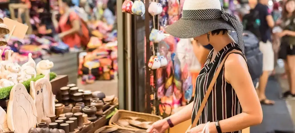 Traveler browsing handcrafted souvenirs at vibrant Bangkok street market showcasing local Thai culture