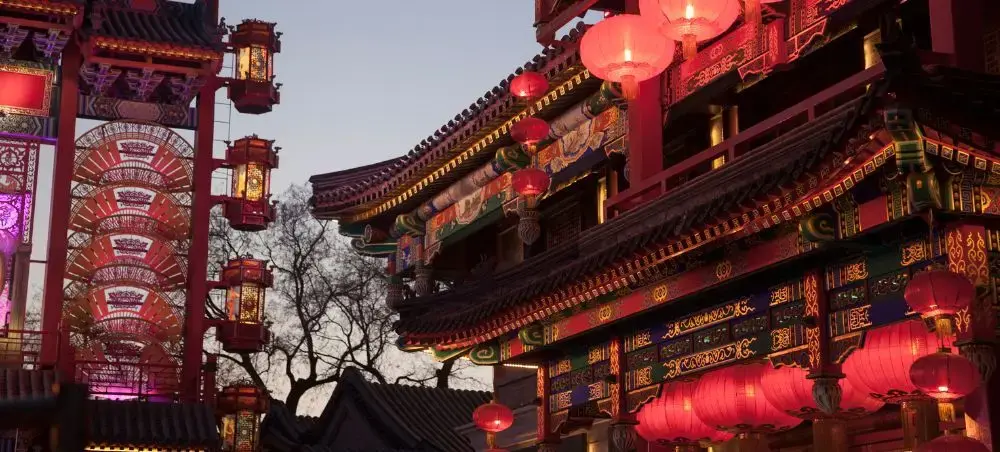 Traditional Beijing architecture with red lanterns illuminating historic buildings at dusk in China's capital